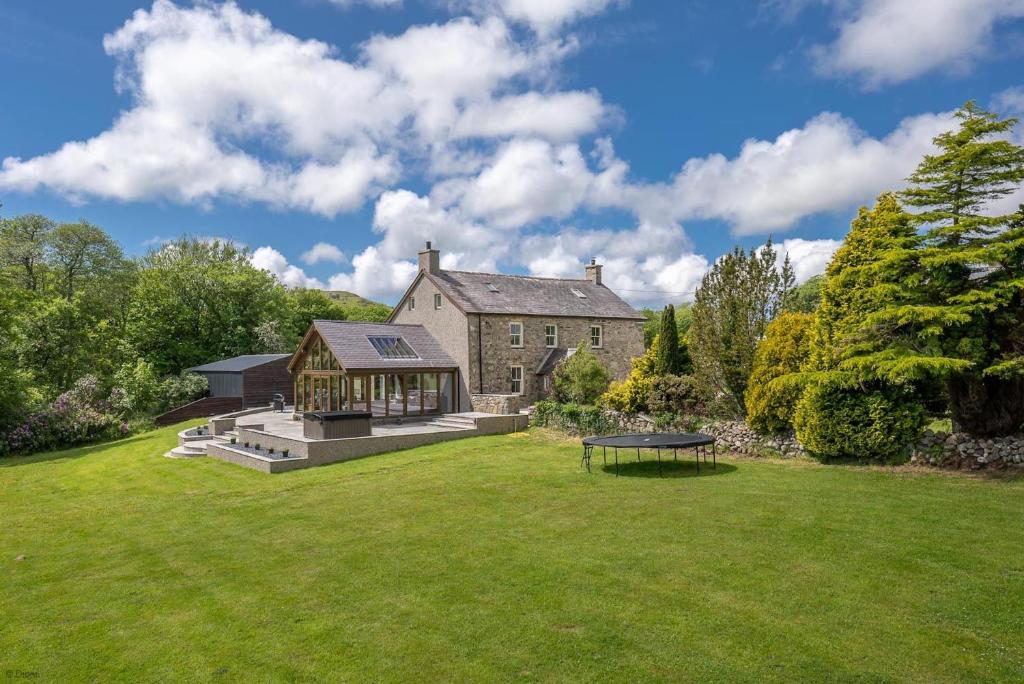 a large stone house with a table in the yard at Ty-Newydd-Llannor in Llannor