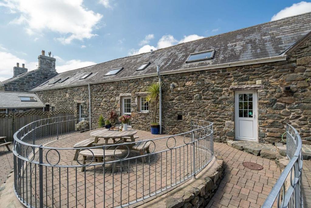 a stone house with a patio and a table at Ysgubor-Sarn in Sarn
