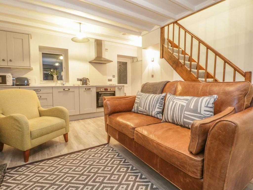 een woonkamer met een bruine bank en een keuken bij Riverside Cottage in Conwy