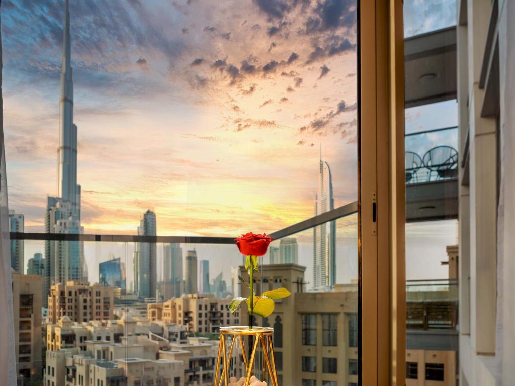 a vase with a red rose sitting in a window at Wake Up to Burj Khalifa l Modern New 1BR Apartment in the Heart of Downtown Dubai in Dubai