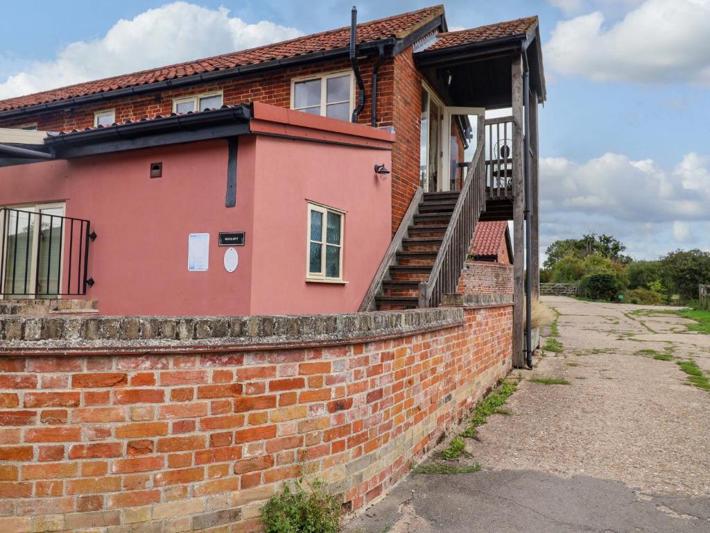 une maison en briques avec un escalier sur un mur de briques dans l'établissement Hayloft, à Henley