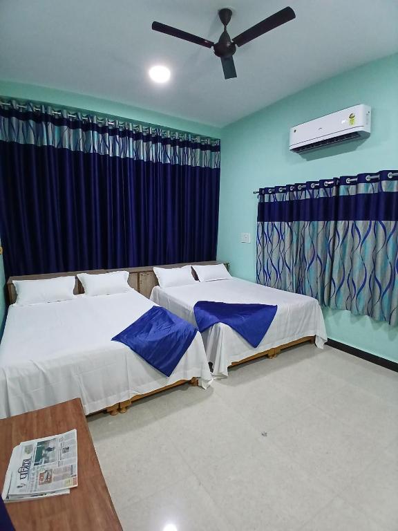 two beds in a room with blue walls at Shree DashbhujaNath Stays in Ujjain