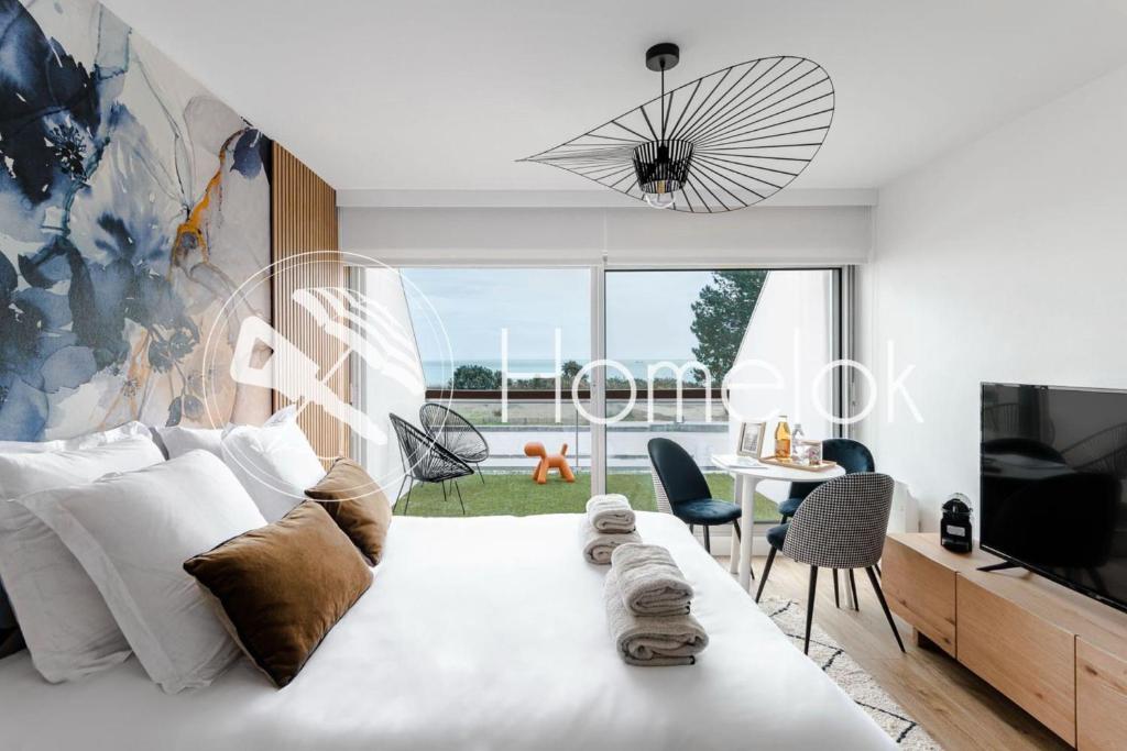 a white bedroom with a large bed and a tv at Horizon bleu depuis un studio unique in Carnac