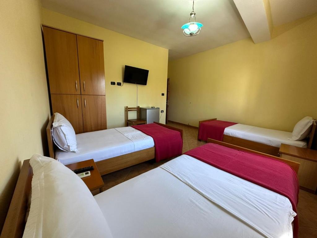 a hotel room with two beds and a tv at Hotel Kudhesi in Vlorë