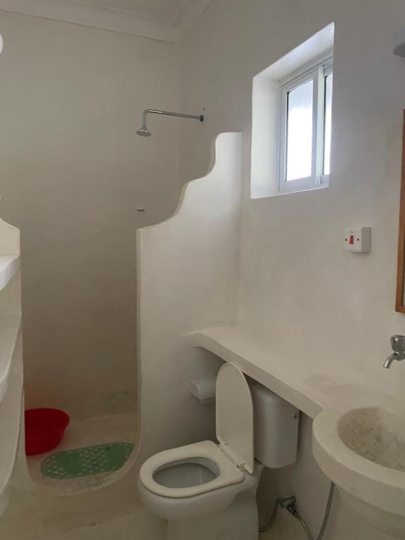 a white bathroom with a toilet and a sink at Watamu 2B in Watamu