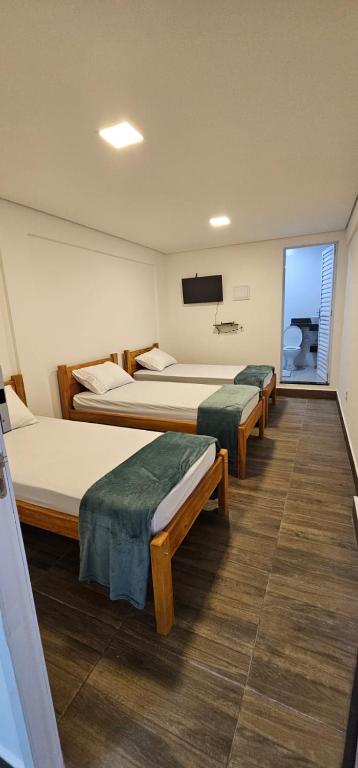 a hotel room with three beds and a flat screen tv at Dima's in Porto Seguro