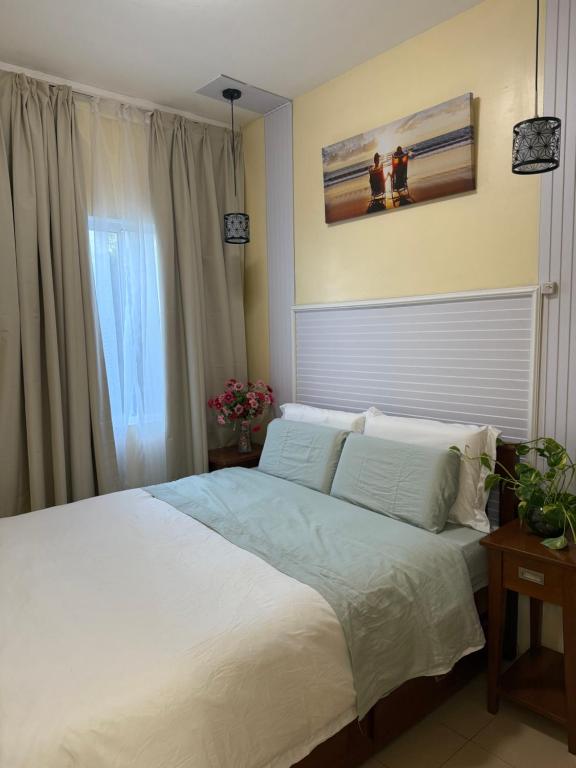 a bedroom with a white bed and a window at DaLei 3- 103 Sleeps 8pax at Marina Spatial Condominium in Dumaguete City in Dumaguete