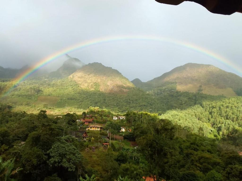 a rainbow over a valley with trees and mountains at Refúgio encanto das montanhas in Nova Friburgo