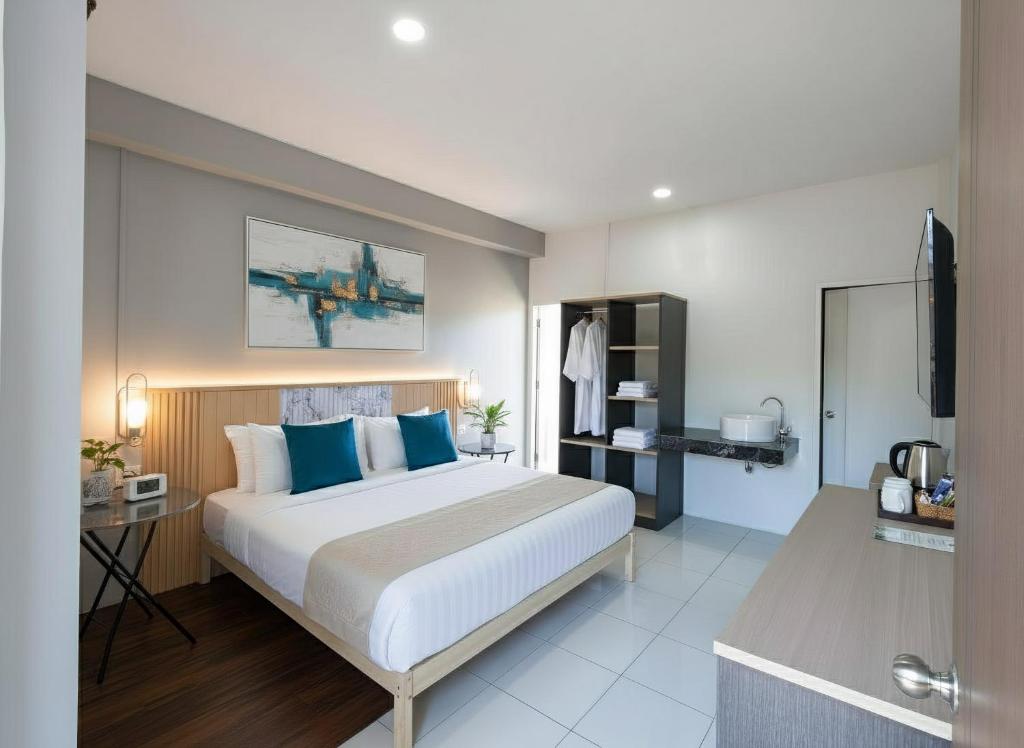 a bedroom with a large bed with blue pillows at Ko Lanta Hotels and Working Space in Ko Lanta