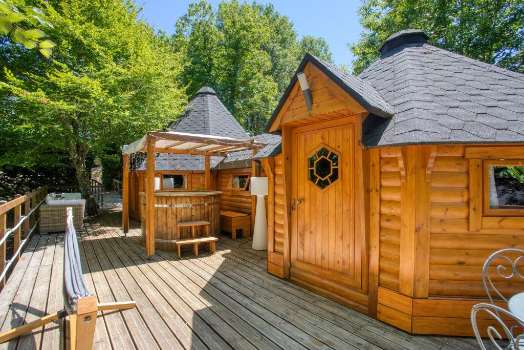 eine große Holzhütte mit einer Bar auf einem Deck in der Unterkunft kota&bain nordique privatif-le bois de la pause- in Saint-Cybranet