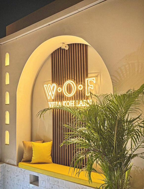 a sign on a wall with a bench and a plant at WOF Villa Kohlarn in Ko Larn