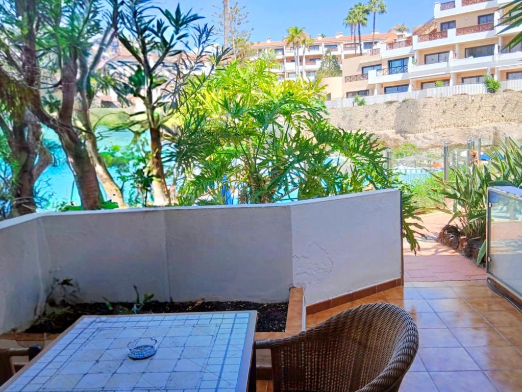 eine Terrasse mit Tisch und Stühlen und ein Gebäude in der Unterkunft Appartamento Parque Albatros vista piscina e mare in San Miguel de Abona