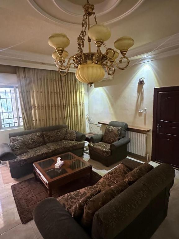 a living room with a couch and a chandelier at Family apartment in Amman 3 bedrooms in Amman
