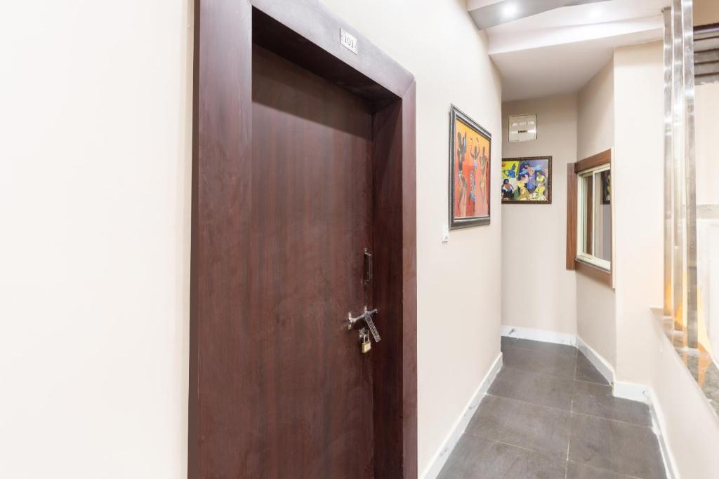 a wooden door in a hallway with a tile floor at Hotel O Savitri Regency in Bhopal