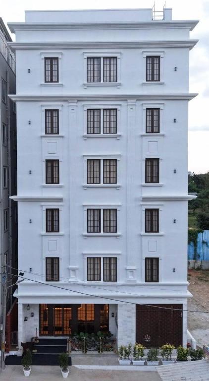 a white building with black windows on a street at ROYAL ACE BOUTIQUE HOTEL - Bhartiya City in Bengaluru