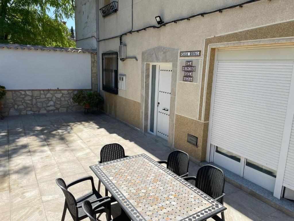 a patio with a table and chairs in front of a building at El Rincón del Agua in Mogón