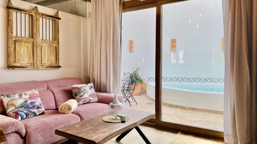 a living room with a pink couch and a table at Al Zahra Suites in Zahara de la Sierra
