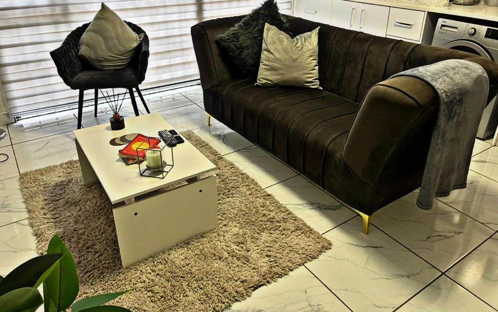a living room with a black couch and a table at Luxury Garden Cottage in Welkom in Welkom