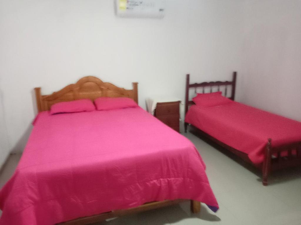 GuararéにあるNanny Villageのピンクのシーツが敷かれた部屋にベッドが2つ