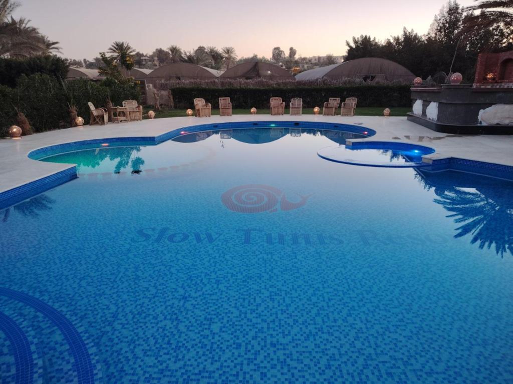 a swimming pool in a resort with blue water at Slow Tunis in Fayoum Center
