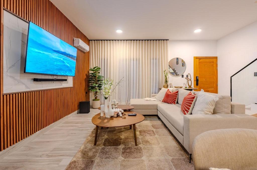 een woonkamer met een bank en een tv aan de muur bij Private Villa in Punta Cana with Pool and Jacuzzi in Punta Cana