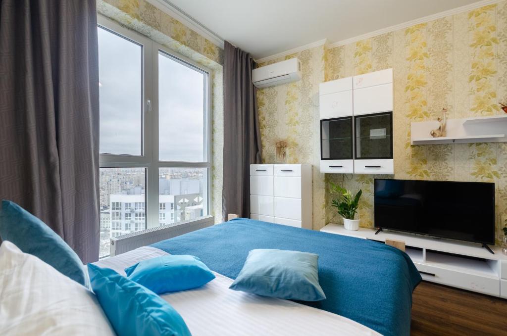 Un dormitorio con una cama azul y una gran ventana. en Panoramic view of the lake in the new apartment, en Kiev