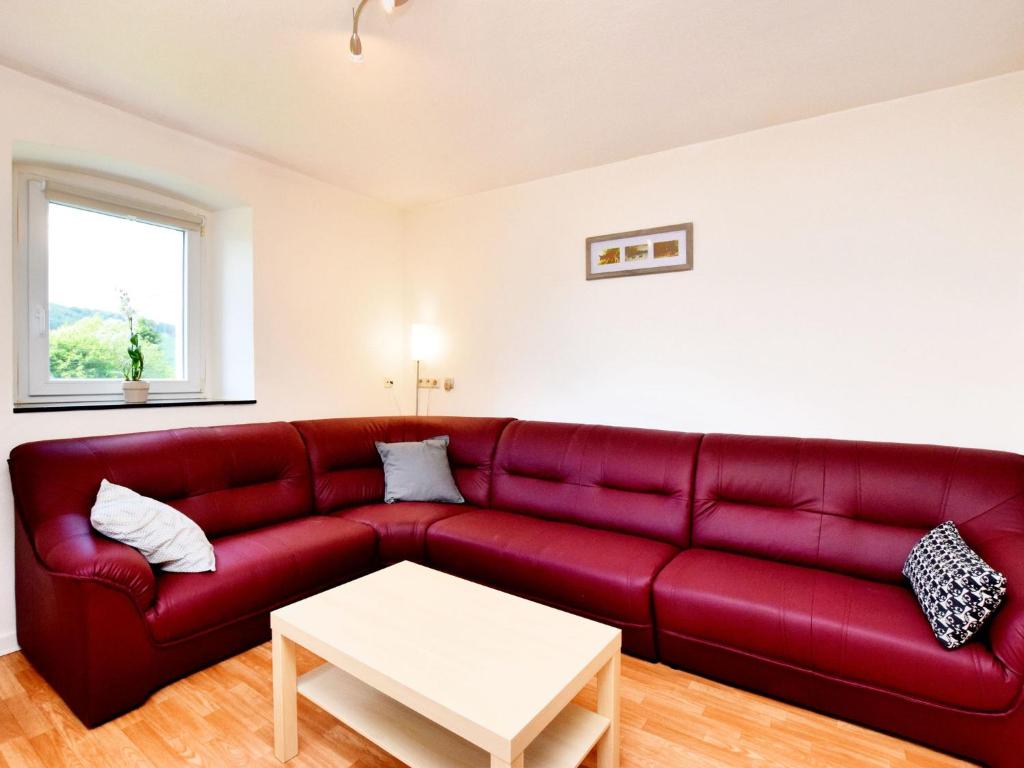 a red couch in a living room with a table at Spacious Holiday Home in Saint Vith with Terrace in Schoenberg