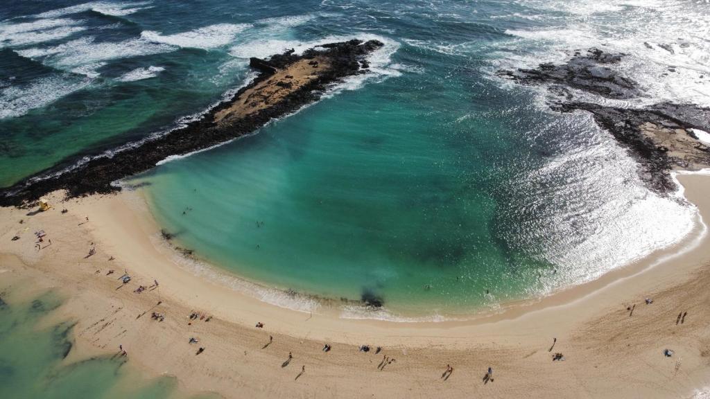 コティージョにあるLa Concha sunsetの海の近くのビーチにいる人々のグループ