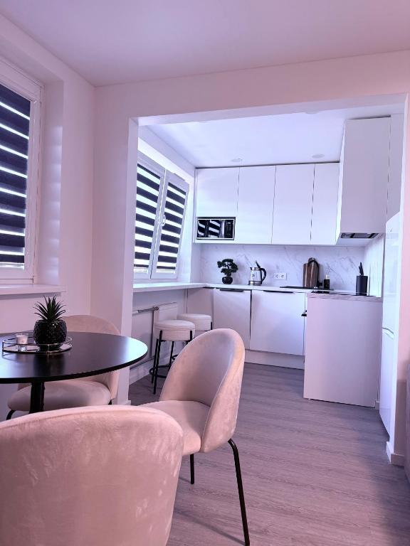 a kitchen with white cabinets and a table and chairs at Feliz Stay in Šiauliai