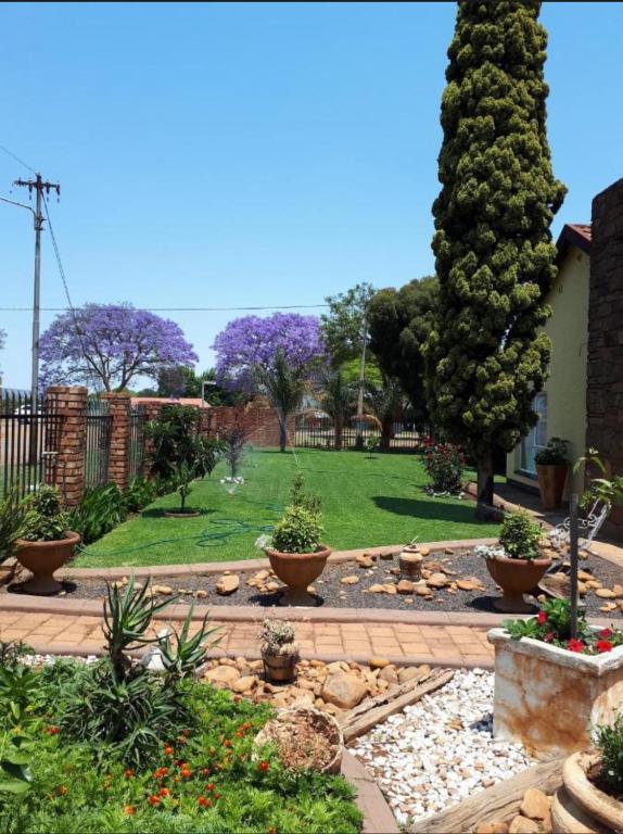a garden with trees and a lawn with flowers at ForgetMeNot Guesthouse Lydenburg in Lydenburg