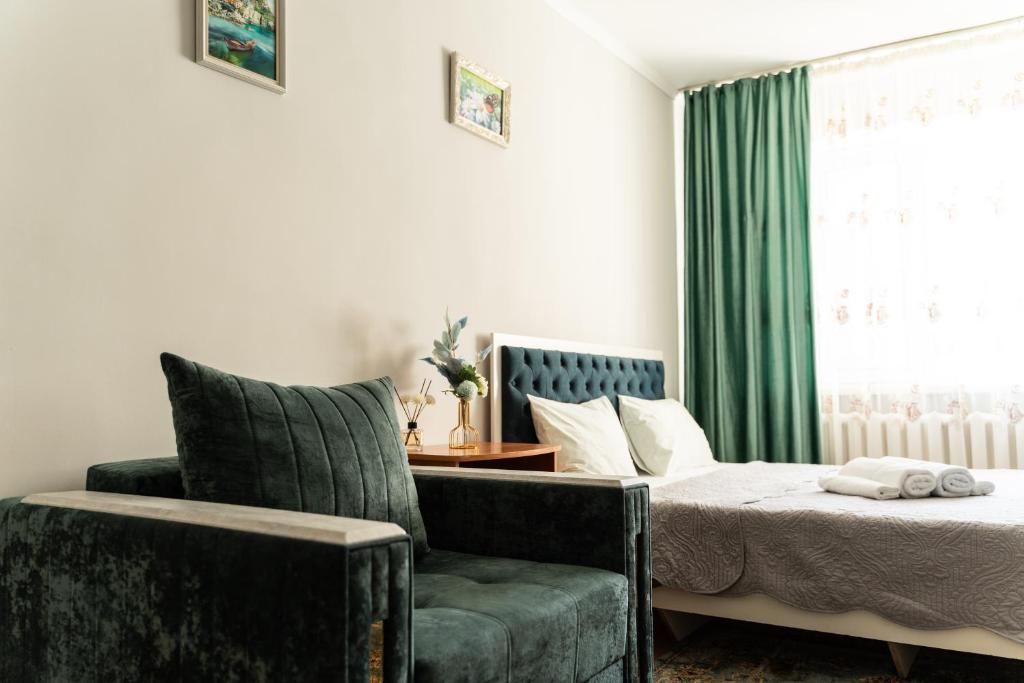 a bedroom with a bed and a chair and a window at Уютная квартира в центре города in Taldykolʼ