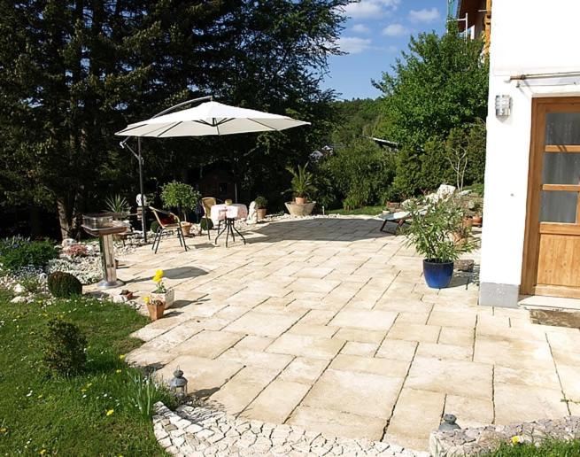 un patio avec un parasol, une table et des chaises dans l'établissement Ferienwohnung Sorpesee, à Sundern