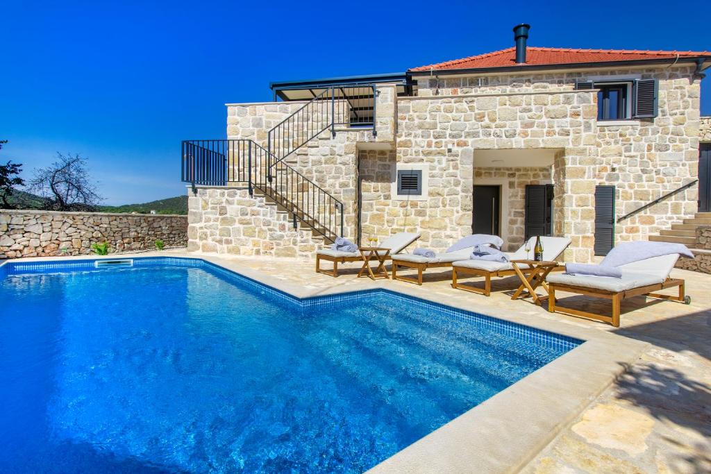 a swimming pool in front of a stone house at Villa Mare Private Stone Villa with Heated Pool and Garden in Vinišće
