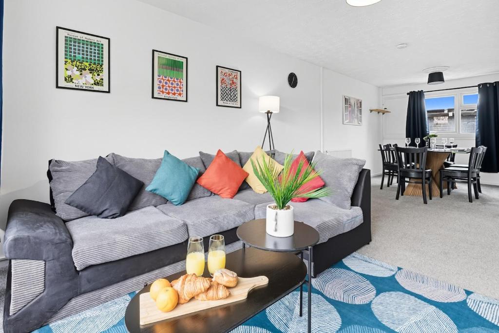 ein Wohnzimmer mit einem grauen Sofa und bunten Kissen in der Unterkunft Cosy 3-Bed Home near Birchwood Business Park by Traboule Properties LTD in Warrington