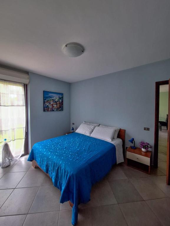 a bedroom with a bed with a blue bedspread at Lago Maggiore Gardens Apartment in Intra