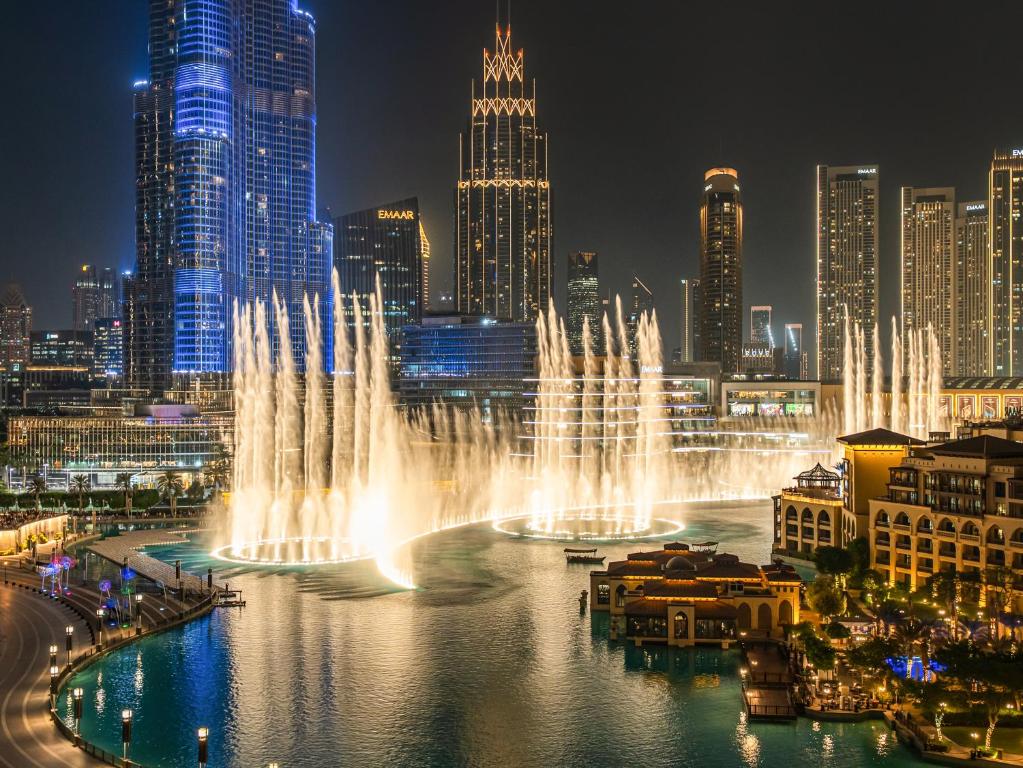a water fountain in the middle of a city at night at Panoramic Burj 5br Condo with Full Led & Fountain View in Dubai
