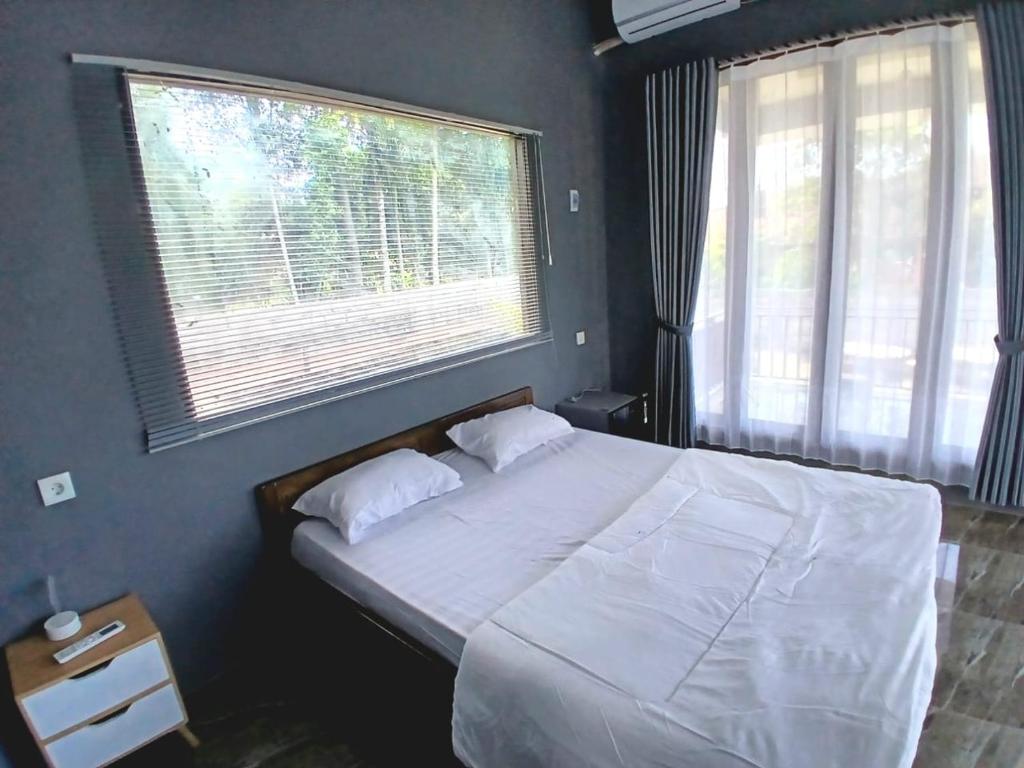 a bedroom with a large bed with two windows at The Mandalika Rinjani Lombok in Masbagik