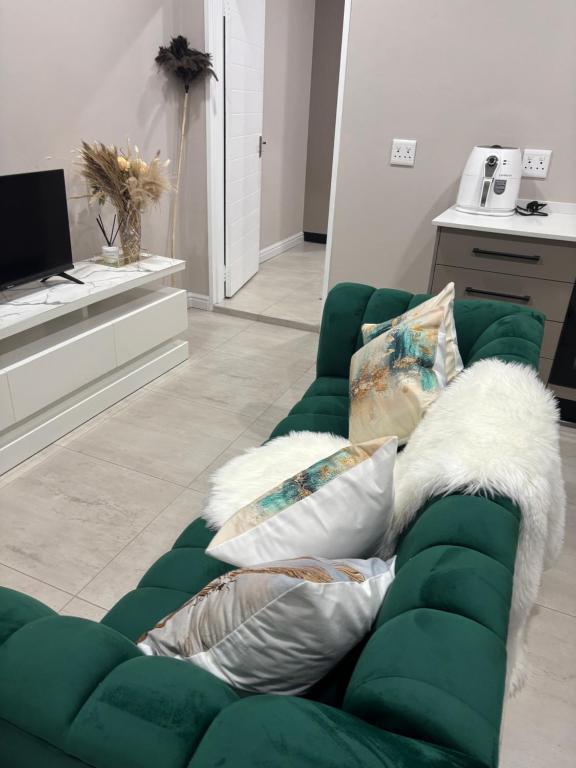 a green couch with pillows in a living room at Tranquil Stays in Polokwane