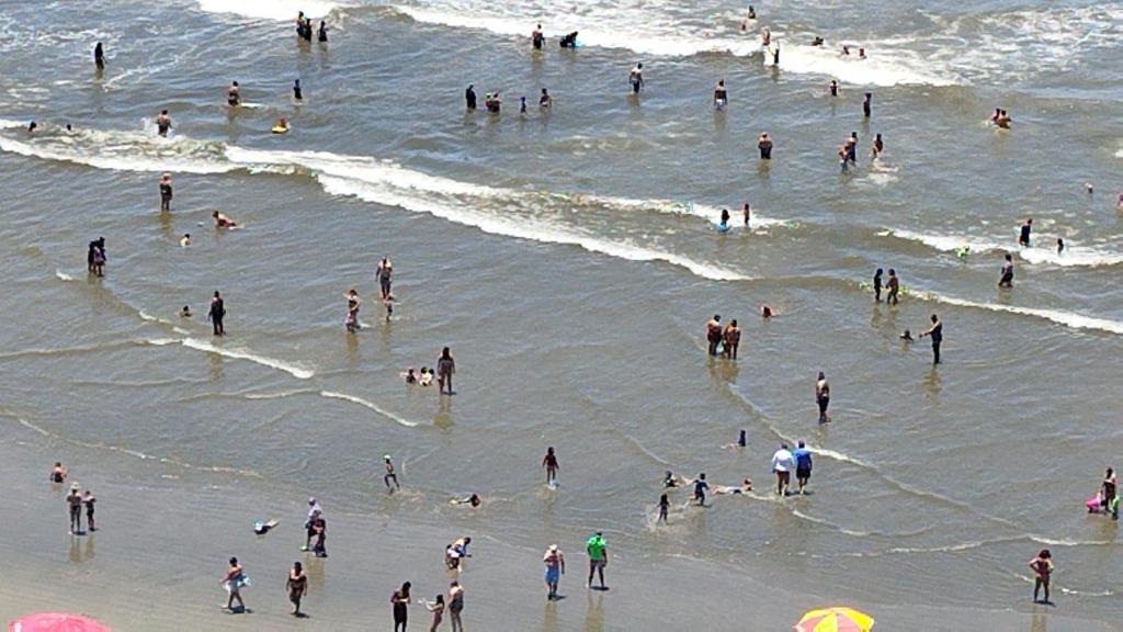 a group of people in the water at the beach at Frente para Mar de água cristalinas in Itanhaém