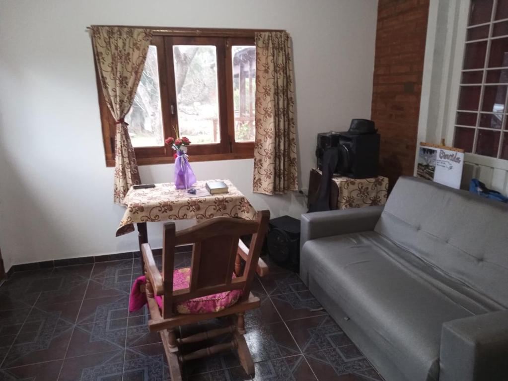 Una sala de estar con un sofá y una mesa y una ventana. en Cabañas La Quiverco, en Balneario Pehuén-Có