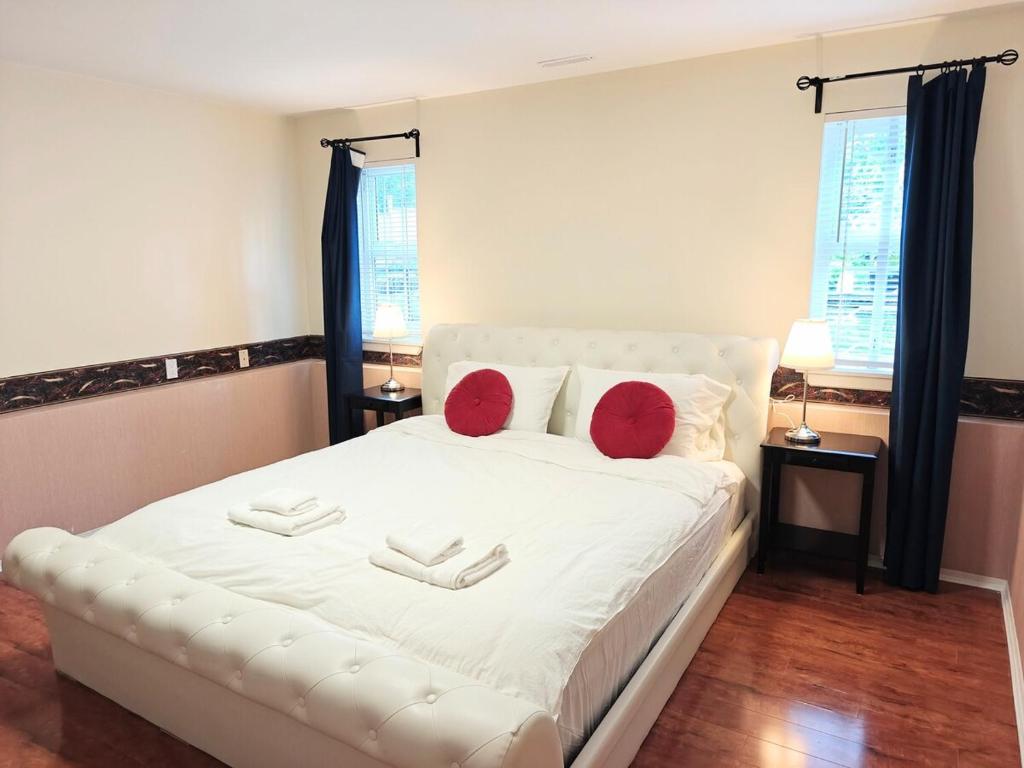 a bedroom with a white bed with red pillows at Charming 1 br Retreat in South Surrey White Rock in Surrey