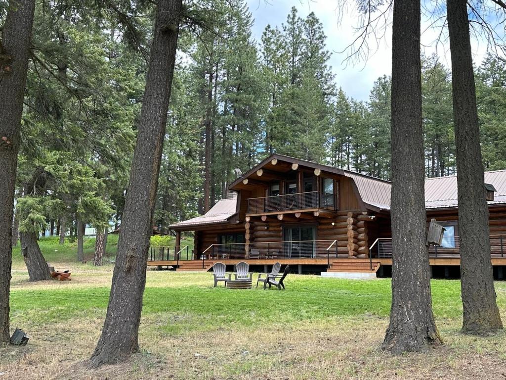 a log cabin in the woods with trees at Living Well Lodge with Panoramic Views in Moyie Springs