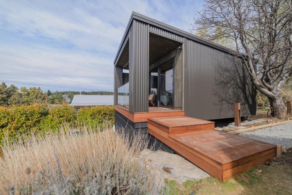 a small house with a wooden deck in a field at Benmore Hideaway Cozy Room with Mini Kitchenette in Lake Tekapo