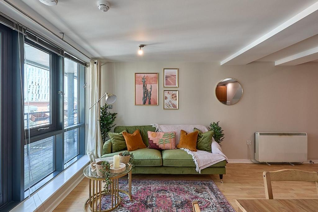 a living room with a green couch and a tv at Luxury 2-Bed Penthouse In Deansgate I Free Parking in Manchester