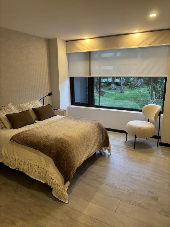 a bedroom with a large window and a bed and a chair at Pucon Infinity Camino al Volcán in Pucón