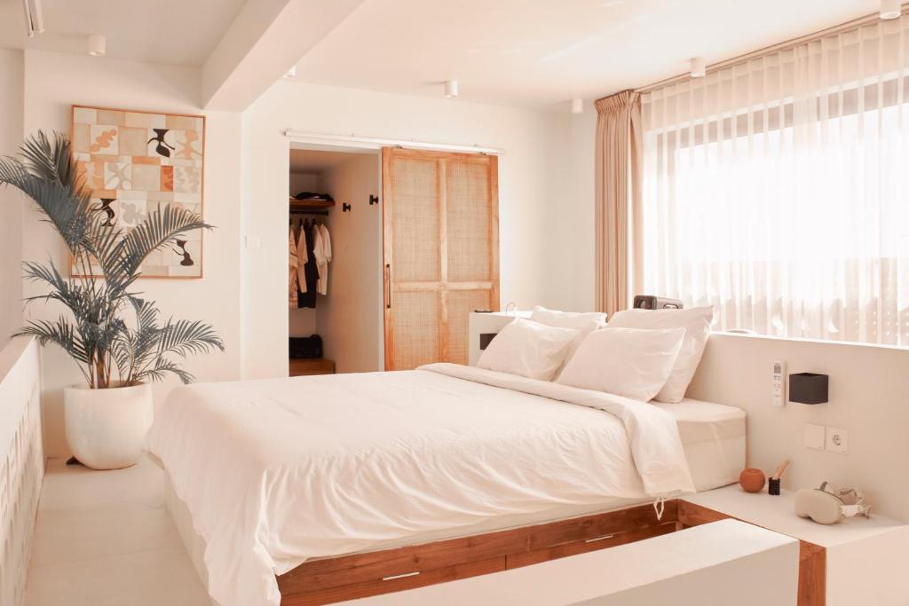 a white bedroom with a large bed and a window at Gate 11 Apartments in Denpasar