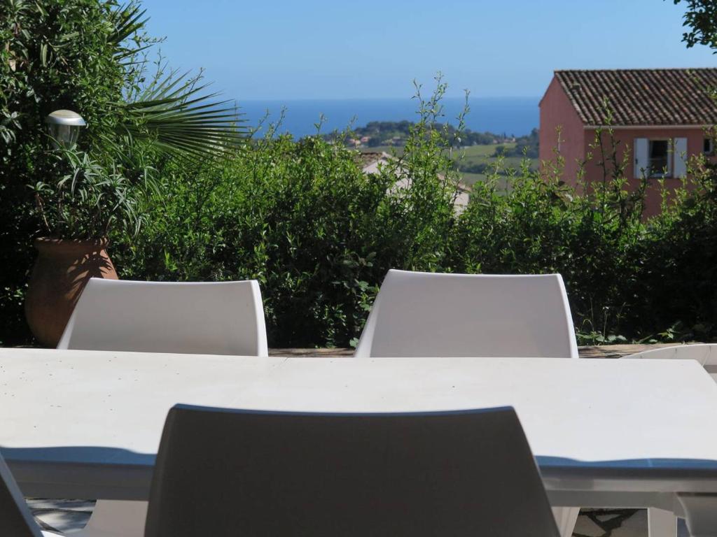- une table et des chaises blanches avec vue sur une maison dans l'établissement Charmant mas 4 personnes avec piscine et parking à La Croix-Valmer - FR-1-726-60, à La Croix-Valmer