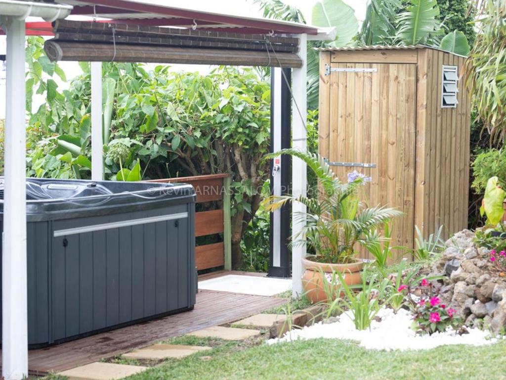 a hot tub in a garden with a wooden deck at Chambre authentique créole aux Avirons - FR-1-786-69 in Ravine Sèche