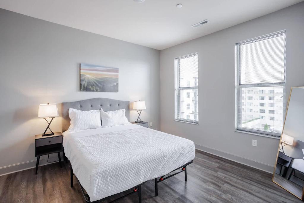 a white bedroom with a bed and two windows at CozySuites at Current the Banks gym pool 01 in Cincinnati
