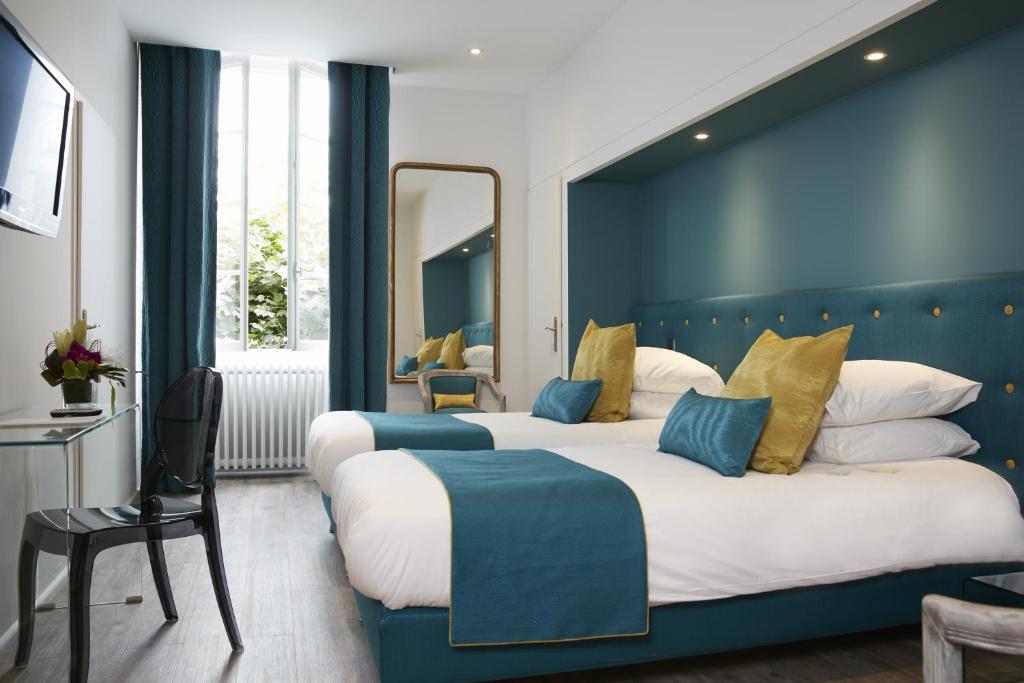 two beds in a hotel room with blue walls at Logis Hôtel - Hôtel Restaurant Maison Claude Darroze in Langon